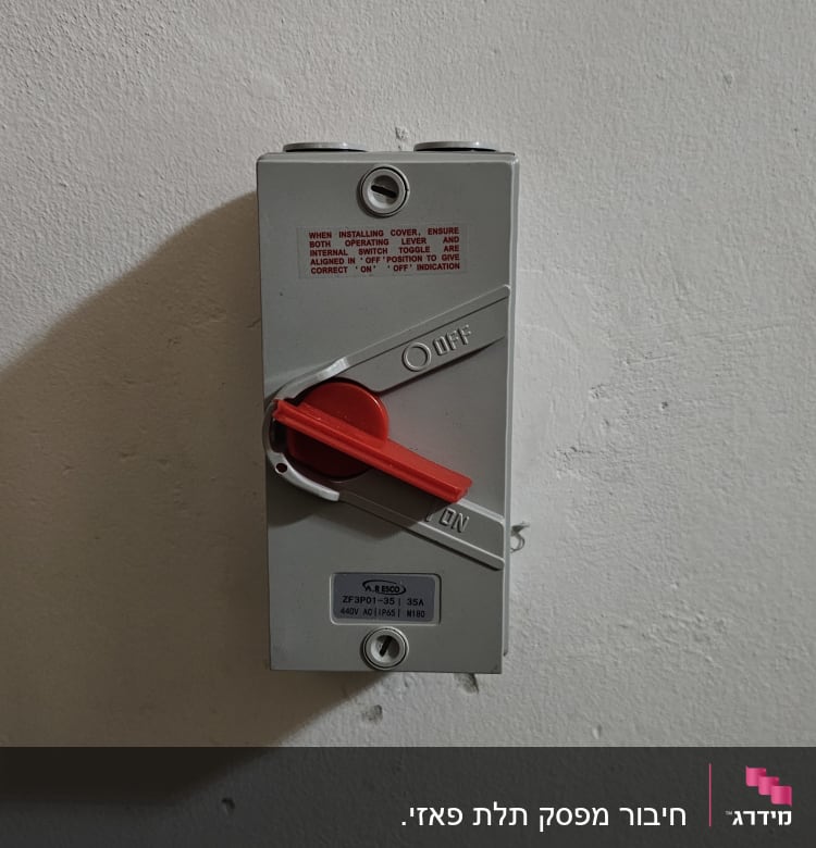 מתג חשמלי עם ידית אדומה על קיר